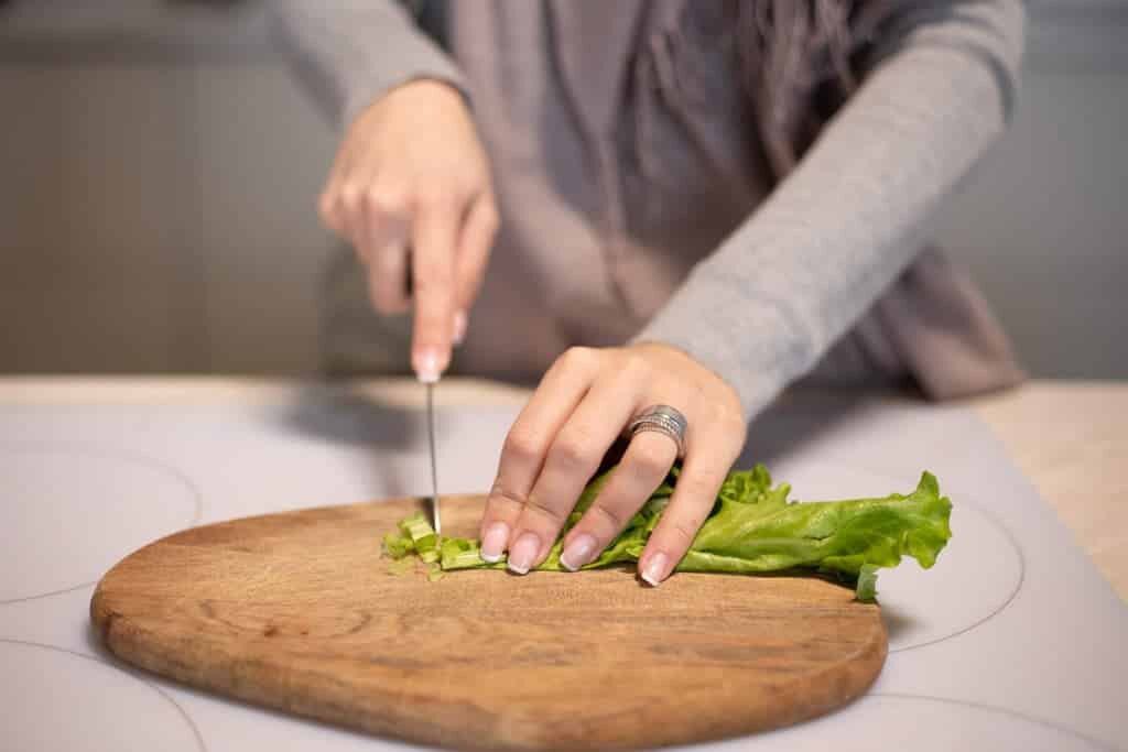 Femme qui coupe de la salade avec un couteau