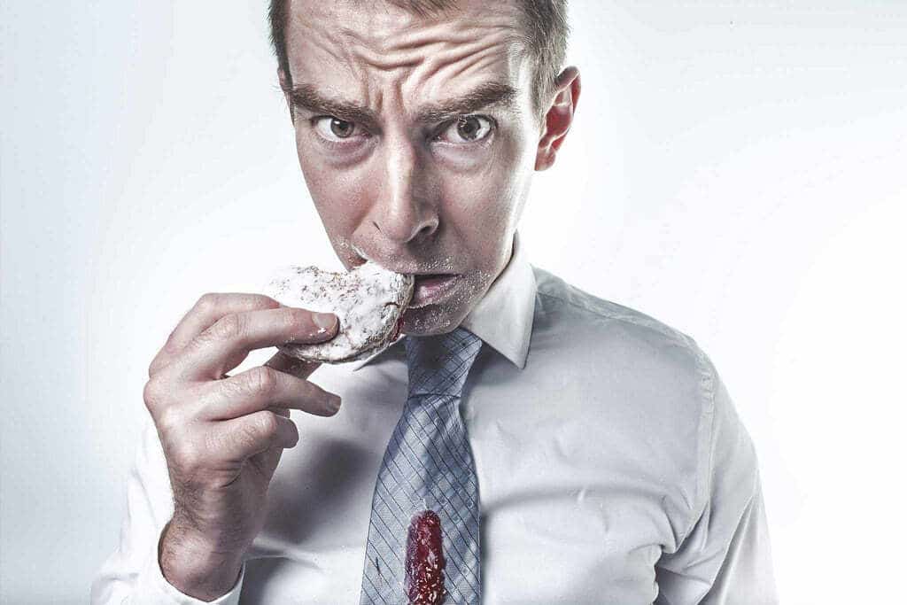 Homme en cravate qui mange un biscuit