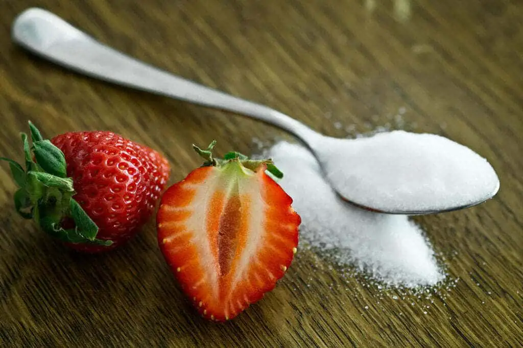 fraise avec cuillère de sucre blanc