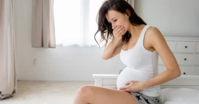 Femme se tenant la bouche et le ventre avec des maux pendant sa grossesse